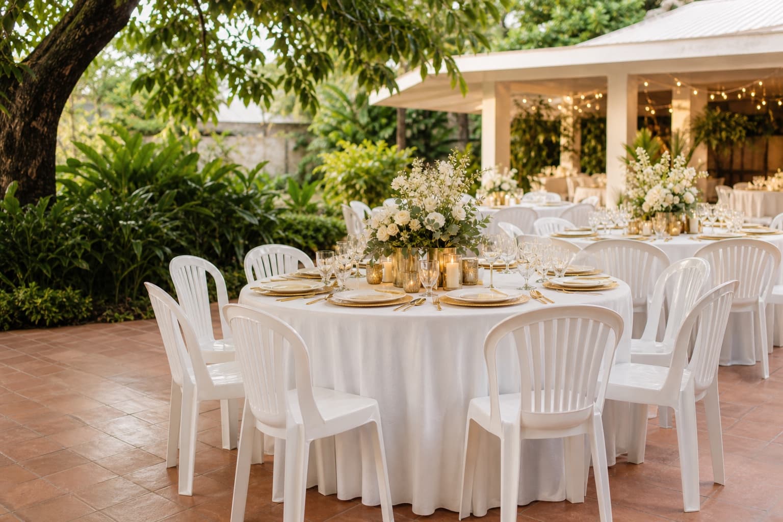Elegant outdoor event setup with white tables, chairs, and warm champagne decor